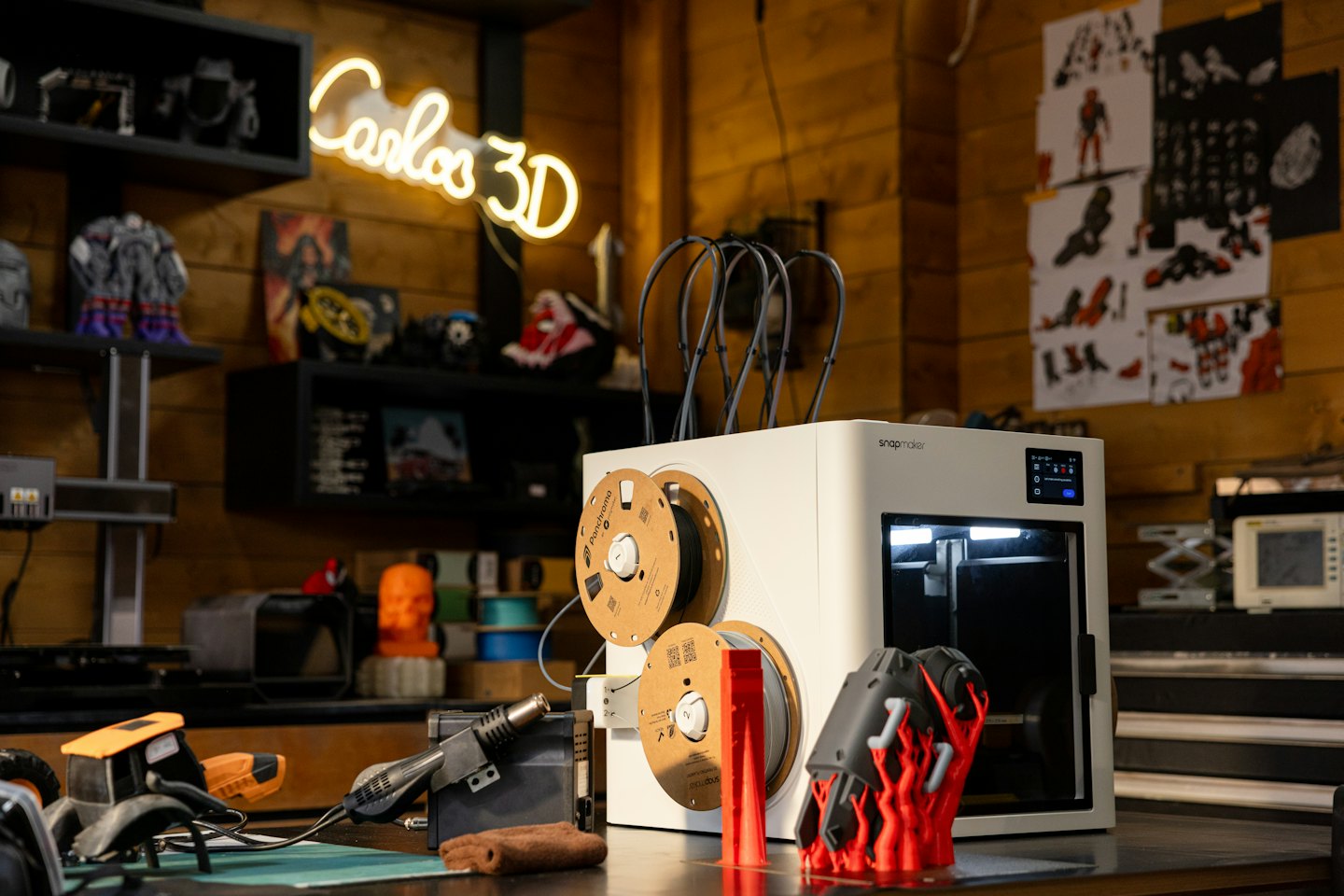 Een moderne 3D-printer maakt een rood object op een werkbank.