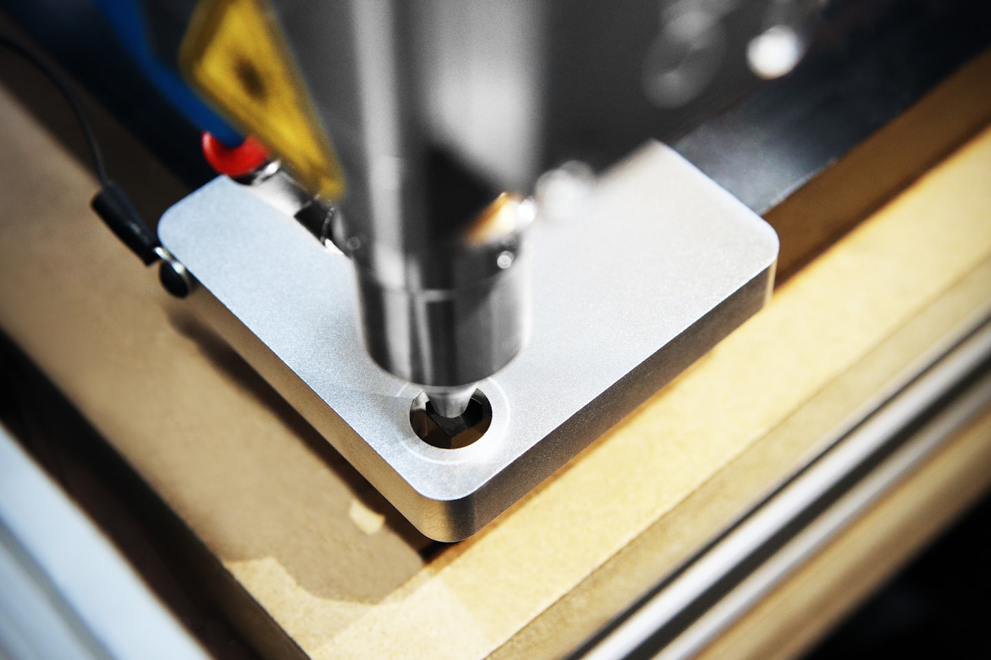 CNC-freesmachine die een rond gat in lichtbruin hout maakt.
