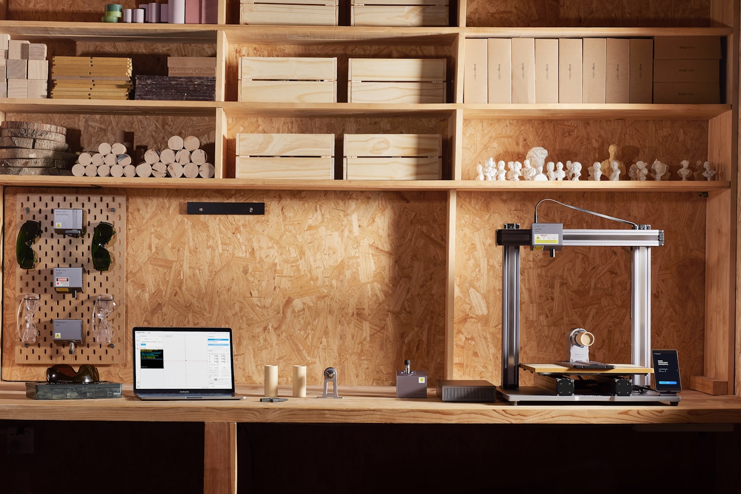 Lasergraveerder en 3D-printer op een werkbank met laptop.