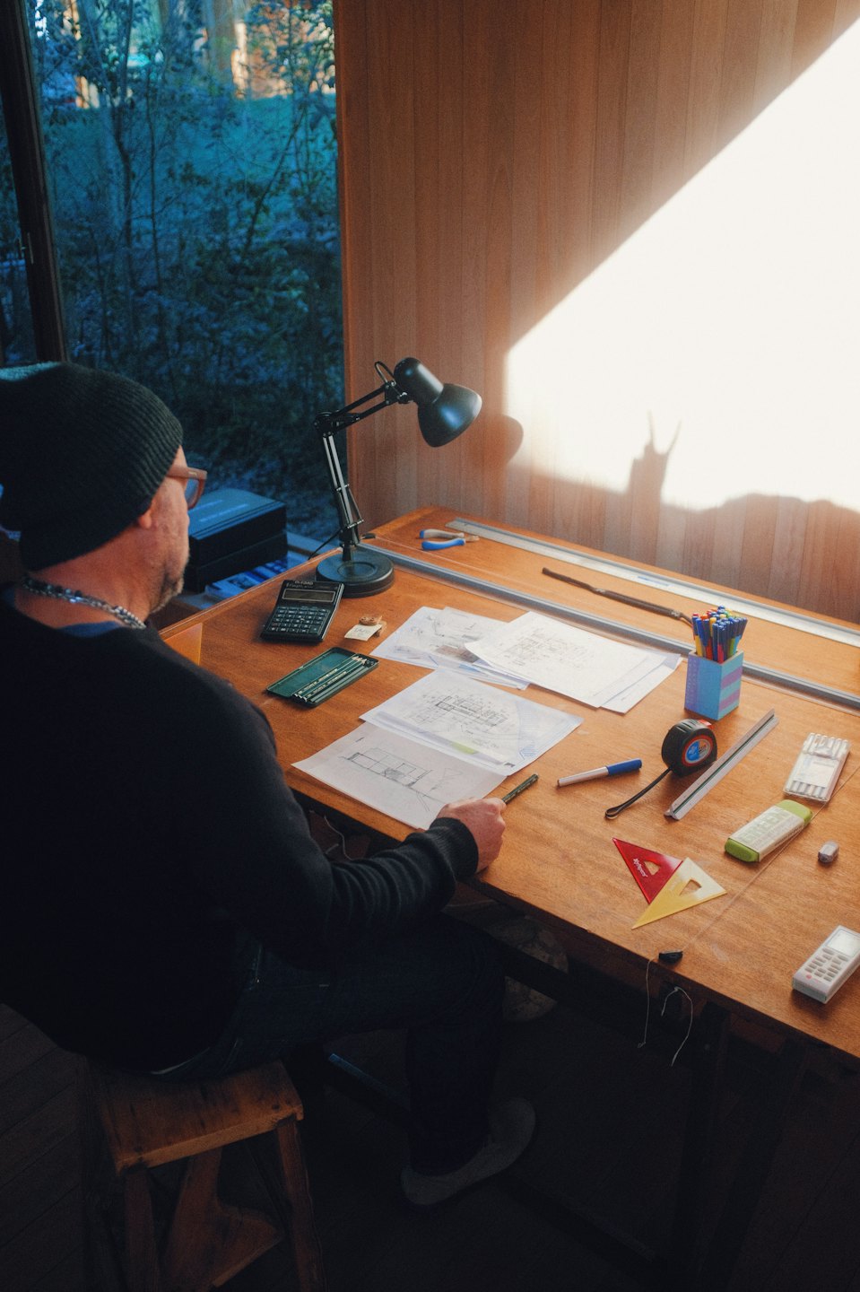 Architect werkt aan blauwdrukken aan een zonnige tekentafel.