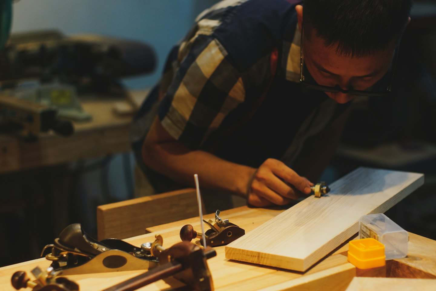 Ambachtsman vormt houten plank met handgereedschap aan werkbank.